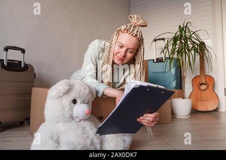 Bella donna matura in abiti casual è impacchettare il suo roba nelle scatole, prendendo appunti. Foto Stock