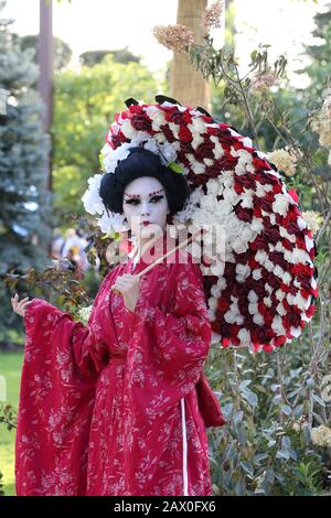 Timisoara, Romania- 09.06.2019 statua vivente di una geisha giapponese. Donna vestita di kimono posa come una statua umana realistica in un parco. Foto Stock