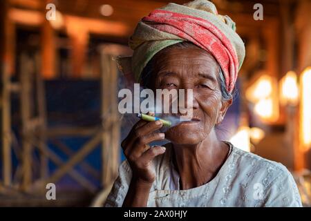 Vecchia signora della minoranza etnica Pa'o che fuma un sigaro birmano al villaggio di Indein vicino al lago di Inle, Stato di Shan, Myanmar (Birmania). Foto Stock