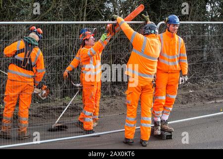 Harefield, Regno Unito. 8 Febbraio 2020. Gli ingegneri HS2 passano una motosega da utilizzare per i lavori di abbattimento di alberi per il collegamento ferroviario ad alta velocità sopra la recinzione in stile Heras su Harvil Road nella Valle di Colne. Credit: Mark Kerrison/Alamy Live News Foto Stock