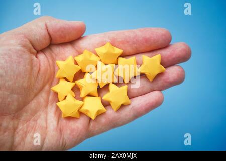 Giallo origami stelle fortunate in una mano. Primo piano. Foto Stock