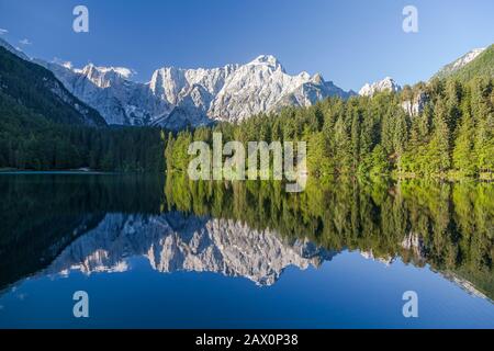 Vista panoramica panoramica dell'idilliaco lago alpino di montagna con riflessi cristallini nella bella luce del mattino all'alba in una giornata di sole in primavera Foto Stock