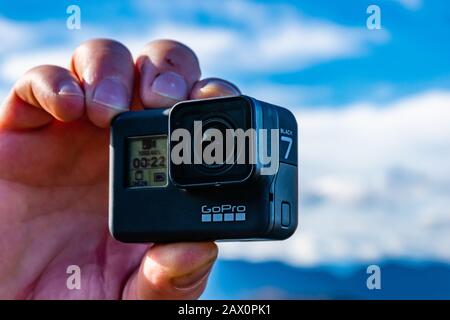 Lucéram, Francia - 2 febbraio 2020: Un uomo che ha una fotocamera GoPro HERO7 Black che guarda un video del paesaggio di montagna durante un'escursione Foto Stock