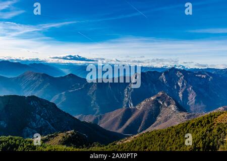 Bellissimo e affascinante paesaggio delle stratificate nebbiose Alpi francesi catena montuosa in Alpes-Maritimes nel pomeriggio durante una giornata di sole Foto Stock