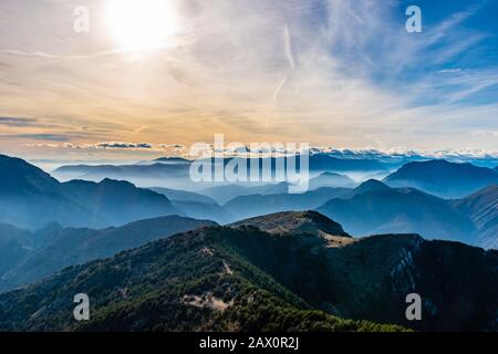 Bellissimo e affascinante paesaggio delle stratificate nebbiose Alpi francesi catena montuosa in Alpes-Maritimes nel pomeriggio durante una giornata di sole Foto Stock