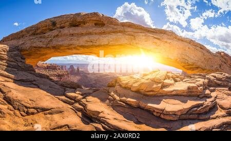 Visualizzazione classica del famoso Mesa Arch, simbolo del sud-ovest americano, illuminata a scenic golden. La luce del mattino al sorgere del sole su una bella giornata in estate Foto Stock