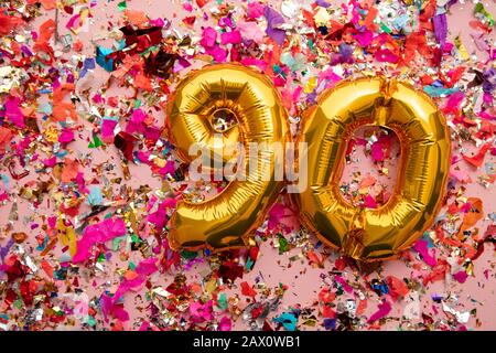 Numero 90 oro compleanno mongolfiera su sfondo confetti glitter Foto Stock