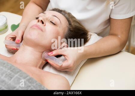 Il closeup della tazza applicato alla pelle del collo di un paziente femminile come parte del metodo tradizionale di terapia della cupping Foto Stock