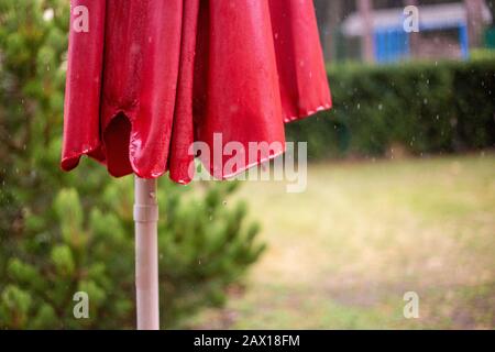 un ombrellone rosso bagnato in estate pioggia con gocce di pioggia Foto Stock