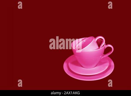 Coppia di set da tè rosa di diverse dimensioni su sfondo rosso marrone Foto Stock