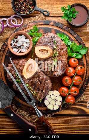 Stinco di vitello e condimenti per la produzione di osso Buo su tagliere di legno. Vista dall'alto. Spazio libero per il testo. Foto Stock