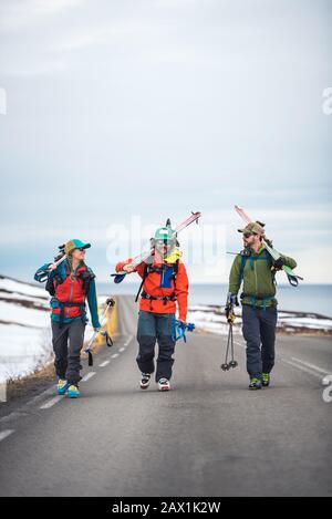 Tre persone che camminano lungo una strada asfaltata in Islanda Foto Stock