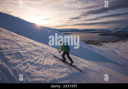 Uomo sciando in Islanda all'alba con acqua dietro di lui Foto Stock