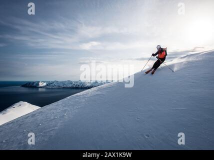 Un uomo che scia in discesa con l'oceano sullo sfondo in Islanda Foto Stock