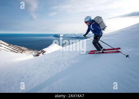 Un uomo che scia in discesa con l'oceano sullo sfondo in Islanda Foto Stock