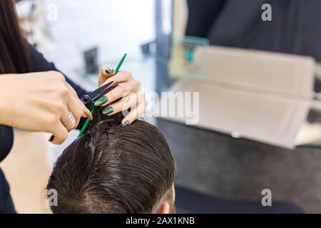 Le mani del parrucchiere femminile che fanno il haircut per il cliente maschio usando gli attrezzi professionali del parrucchiere forbici, spazzola sullo spazio di lavoro del parrucchiere. Parrucchiere Foto Stock
