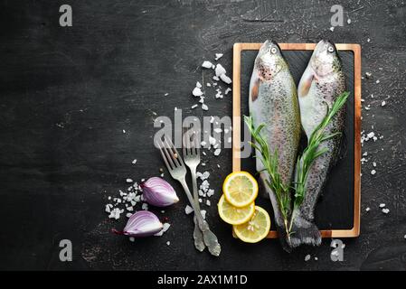 Pesce crudo con verdure su fondo di legno nero. Trota di pesce. Vista dall'alto. Spazio libero per il testo. Foto Stock