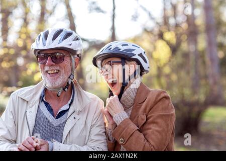 Donna anziana e uomo in parco con biciclette Foto Stock