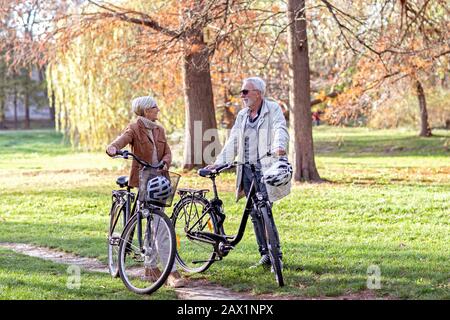 Donna anziana e uomo in parco con biciclette Foto Stock