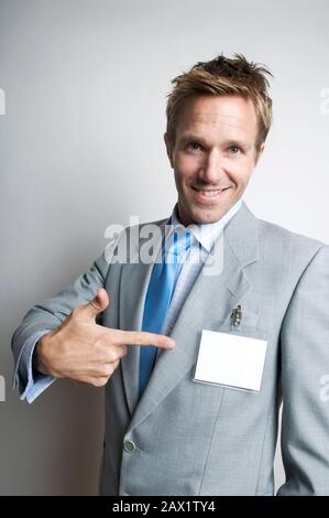 Imprenditore sorridente rivolta con un allegro espressione al suo nome vuoto tag Foto Stock