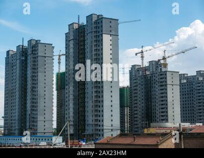 Alto complesso di appartamenti a torre sotto costruzione che torreggia sopra edifici tradizionali, Jining, Cina, Asia Foto Stock