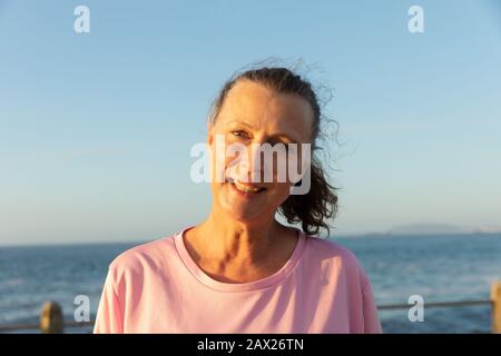 Pareggiatore femminile che guarda la macchina fotografica sul mare Foto Stock