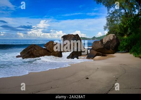 Onde dell'oceano e rocce di granito - Baie Lazare Beach, Mahe Island, Seychelles. Foto Stock