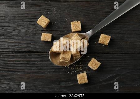 Cucchiaio con cubetti di zucchero su fondo di legno, vista dall'alto Foto Stock