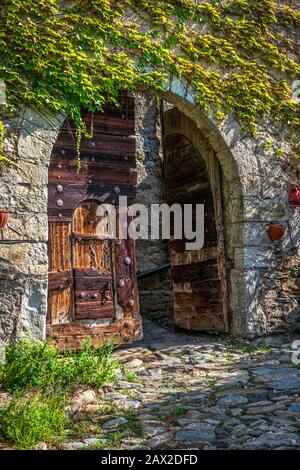 Vecchie porte in legno di un antico castello e un muro di pietra in Alto Adige Foto Stock