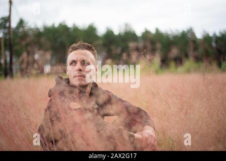 L'uomo siede in un campo spesso, e pensa. Foto Stock