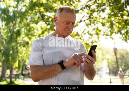 Jogger ascoltare musica e utilizzare il telefono cellulare nel parco Foto Stock