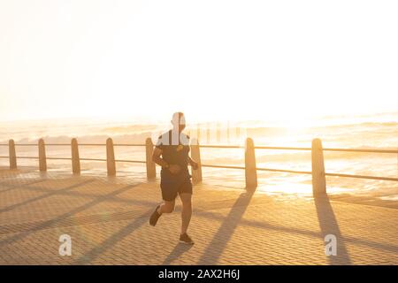 Jogger che corre sul mare al tramonto Foto Stock