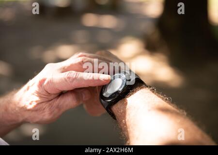 Jogger utilizzando un orologio intelligente nel parco Foto Stock