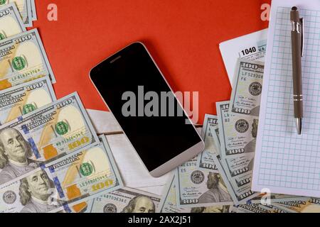 Controllo di retraun con 100 dollari USA valuta e spirale blocco note cellulare Foto Stock