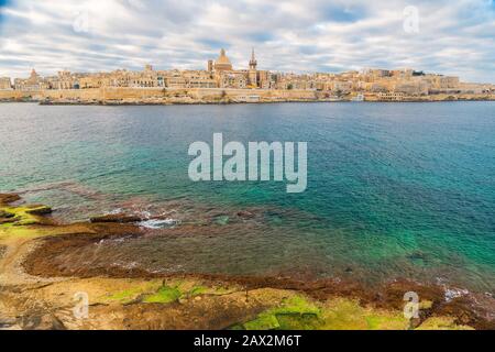 Valletta, lo skyline della città vecchia di Malta dalla città di Sliema sull'altro lato del porto di Marsans durante l'alba Foto Stock