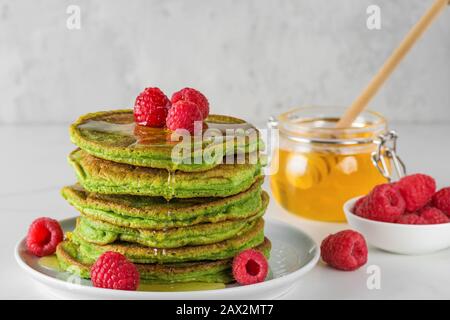 Matcha tè verde frittelle. Mucchio di pancake fatti in casa con lamponi freschi e miele. Colazione sana dessert. Primo piano Foto Stock