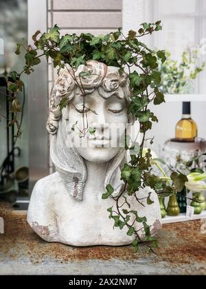 Vaso di fiori di gesso a forma di testa antica di dea con piante