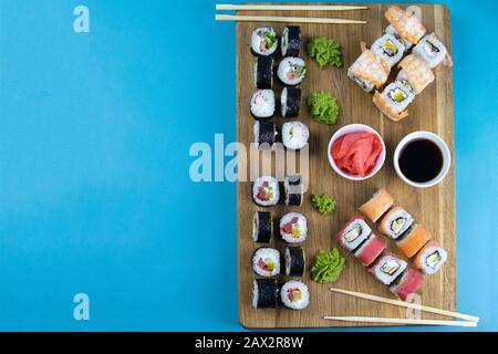 Vista dall'alto del piatto di legno con un'ottima serie di deliziosi sushi Nigiri e rotoli Tempura con rotoli Maki e Uramaki Foto Stock