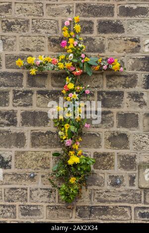 Una croce cristiana floreale al di fuori della chiesa metodista di Baildon nello Yorkshire, Inghilterra. Foto Stock