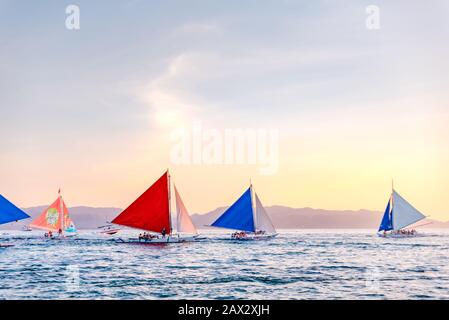 Isola di Boracay, Aklan, Filippine - I Visitatori godono del tramonto in una tradizionale barca a vela alimentata dal vento al tramonto. Circa Gennaio 2020. Foto Stock