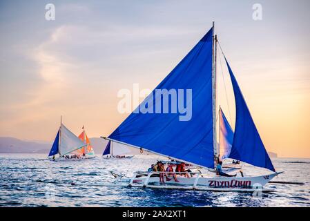 Isola di Boracay, Aklan, Filippine - I Visitatori godono del tramonto in una tradizionale barca a vela alimentata dal vento al tramonto. Circa Gennaio 2020. Foto Stock