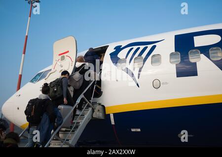 Venezia, Italia - 20 gennaio 2020: Persone in pista per l'aeroporto scale salire a bordo di un volo ryanair a basso costo con cielo blu chiaro durante l'inverno Foto Stock