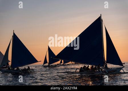 Isola di Boracay, Aklan, Filippine - I Visitatori godono del tramonto in una tradizionale barca a vela alimentata dal vento al tramonto. Circa Gennaio 2020. Foto Stock