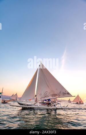 Isola di Boracay, Aklan, Filippine - I Visitatori godono del tramonto in una tradizionale barca a vela alimentata dal vento al tramonto. Circa Gennaio 2020. Foto Stock