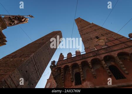 Vista ad angolo basso di due torri (due torri Asinelli e Garisenda) e la statua di San Petronio a Bologna, Italia Foto Stock