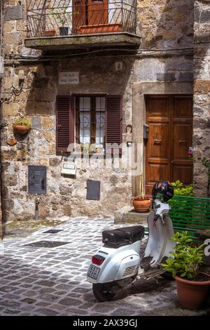 Scooter casa esterna in vendita in vecchia strada acciottolata nella parte vecchia di Bolsena conosciuta per i suoi vicoli stretti, archi e palazzi antichi Foto Stock