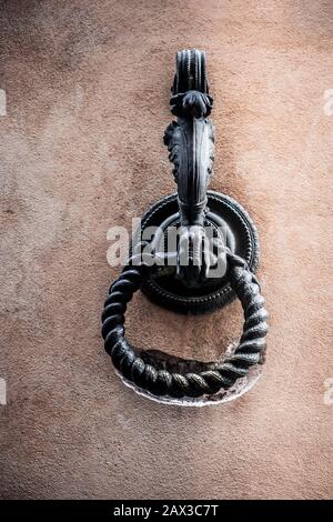 Anello in metallo vecchio decorato originariamente utilizzato per legare i cavalli con l'anello indossato una scanalatura nella vecchia parete Siena, Toscana, Italia Foto Stock
