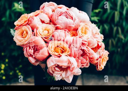 Donna in abito nero è in possesso di Mazzo di rosa le peonie e rose. Concetto di carta, colori pastello di fiori Foto Stock