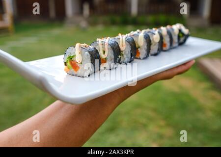 Primo piano di qualcuno che tiene un vassoio di diversi tipi di sushi Foto Stock