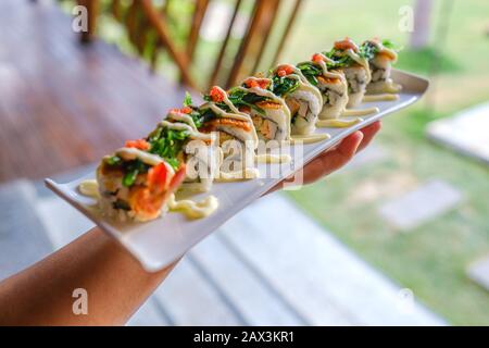 Primo piano di qualcuno che tiene un vassoio di diversi tipi di sushi Foto Stock